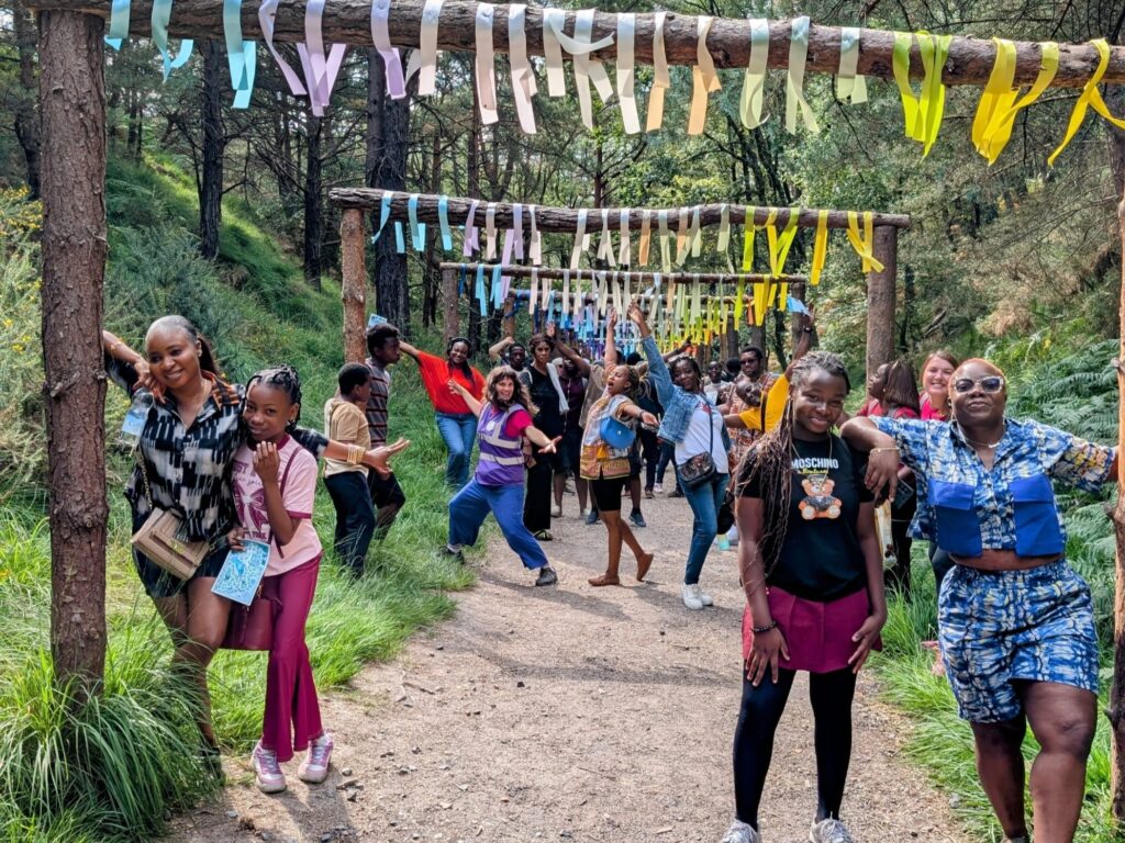 Group of people posing at the Blue Pool under a tunnel of colourful streamers.